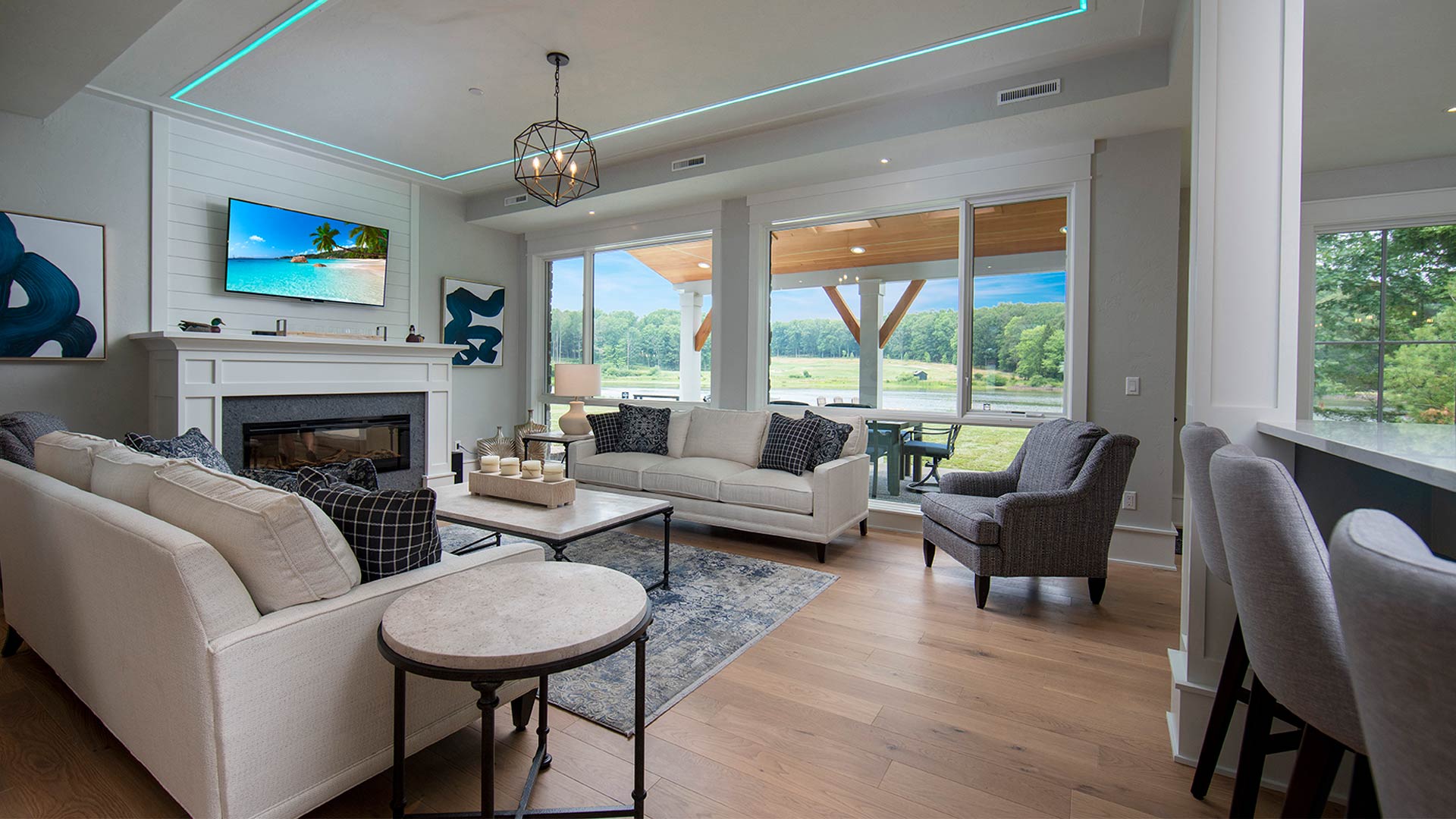 an interior shot of the living area. There are two neutral colored couches across from each other with a coffee table between them. There is a fireplace with modern art pieces on either side of the mantle. There is a sliding glass door leading out to a patio.