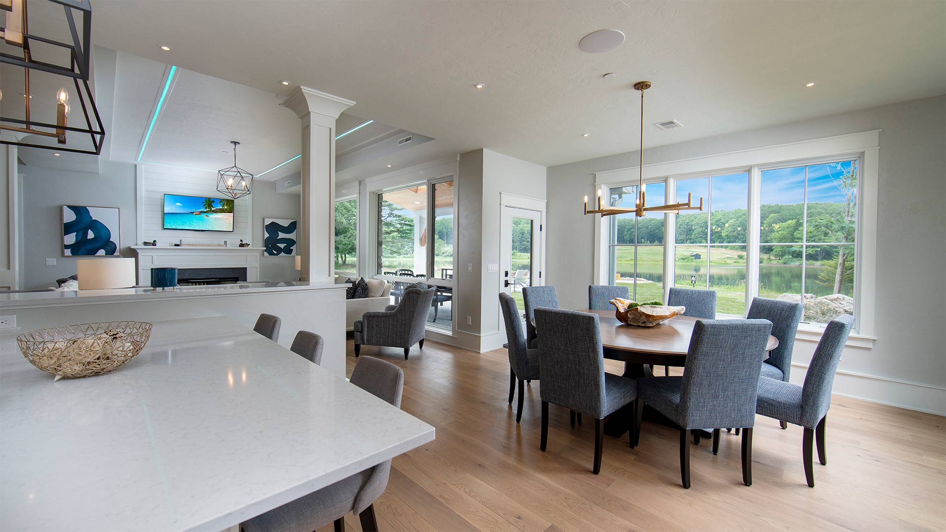 interior shot of the dining area. There are dark grey chairs around a circular table. The floor plan is open so the living room and kitchen as also visible