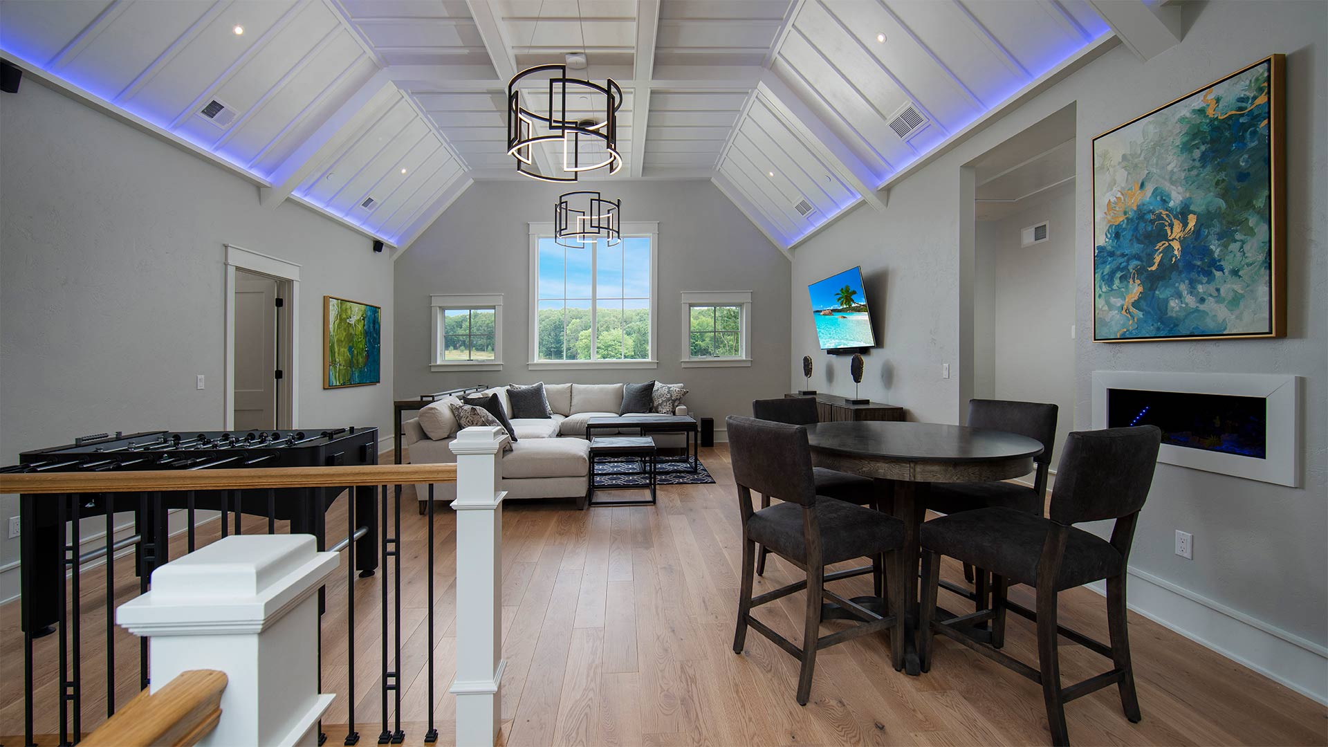 interior shot of an informal living area. There is a couch with a tv mounted on the wall across from it. There is a table and chairs on the other side of the room