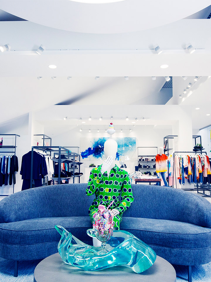 a mannequin sitting on a couch in a clothing store