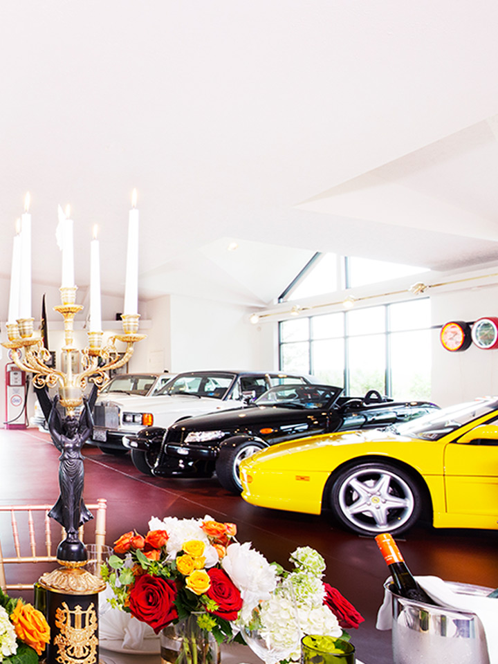 three cars in a showroom with flowers and candles in front
