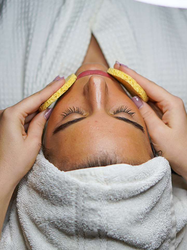 A woman is relaxing while getting a soothing facial.