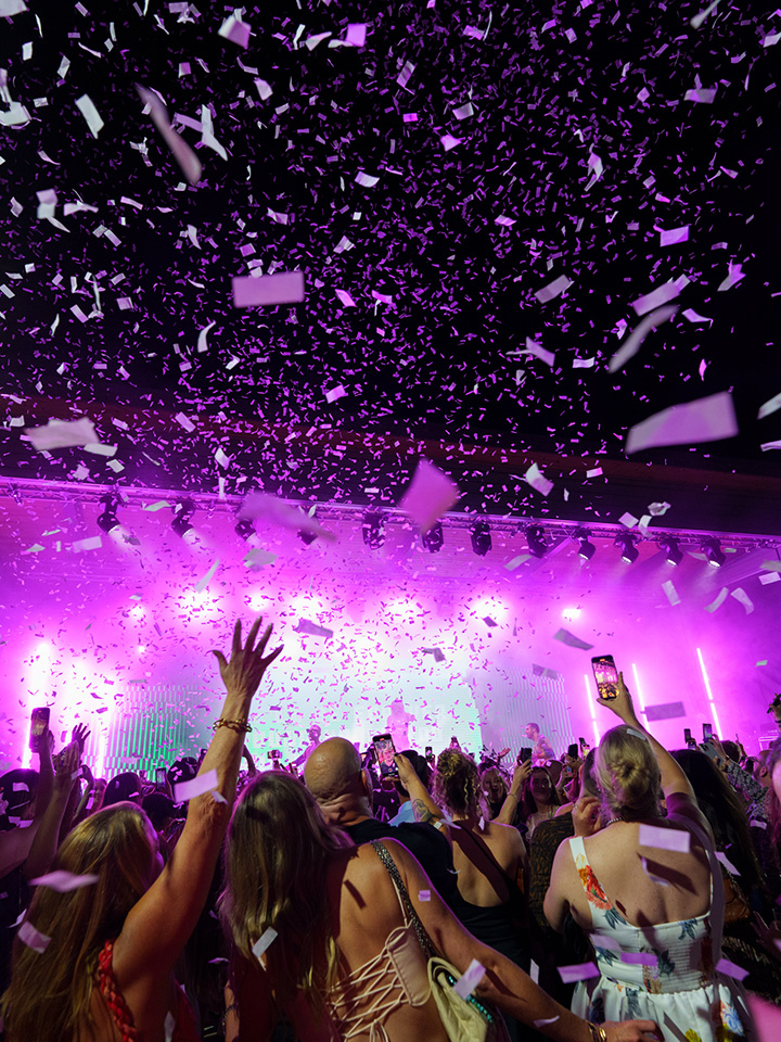 image of people at a concert with purple lighting and confetti falling