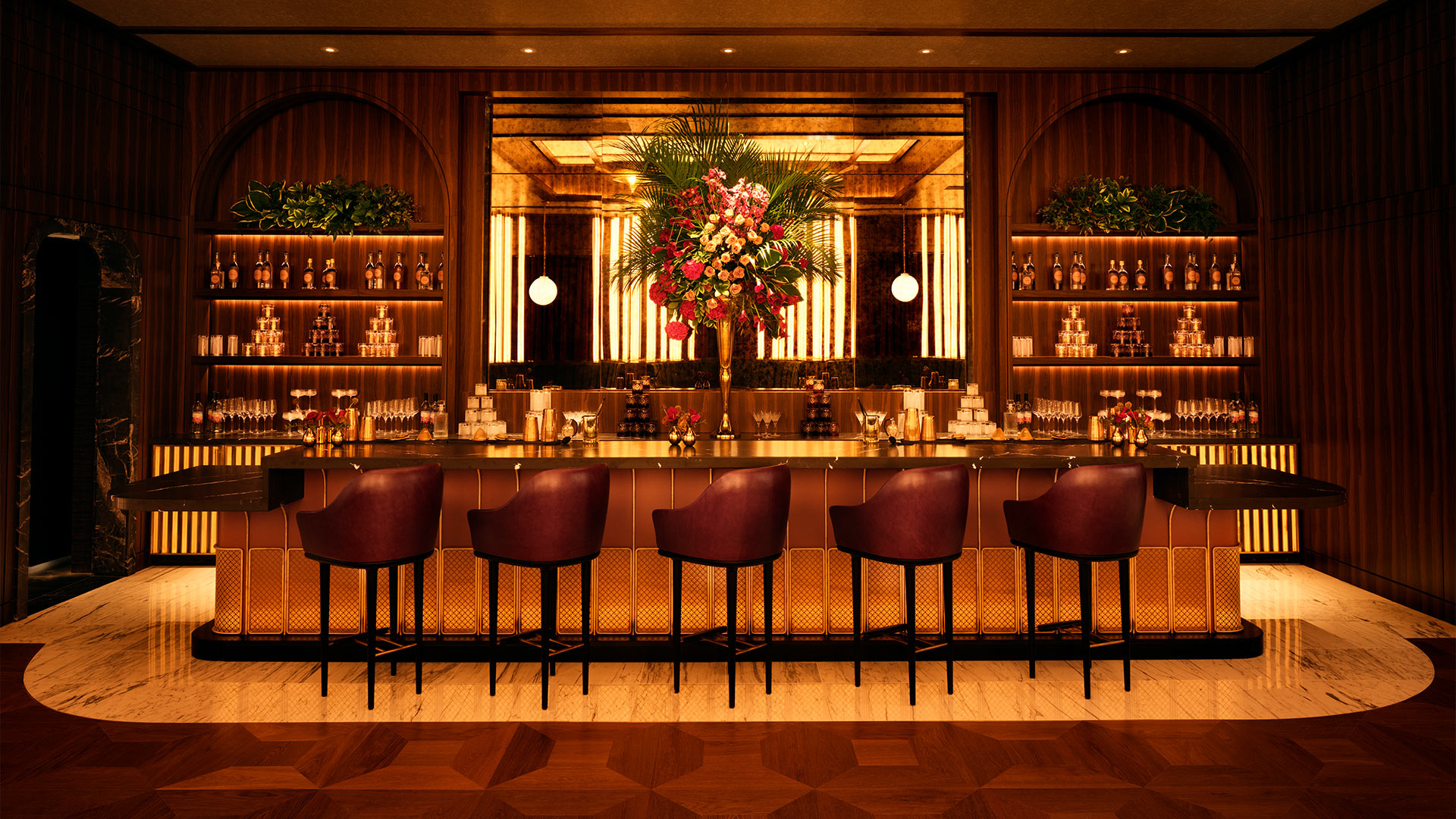 Image of the empty bar with gold lighting, bar stools and a stocked bar.
