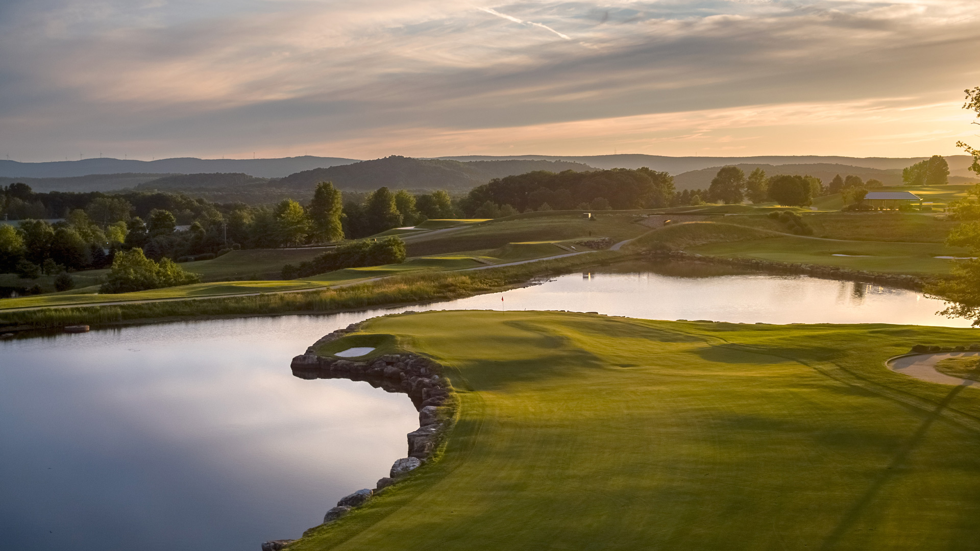 Misty golf course with natural pond and green lawn.