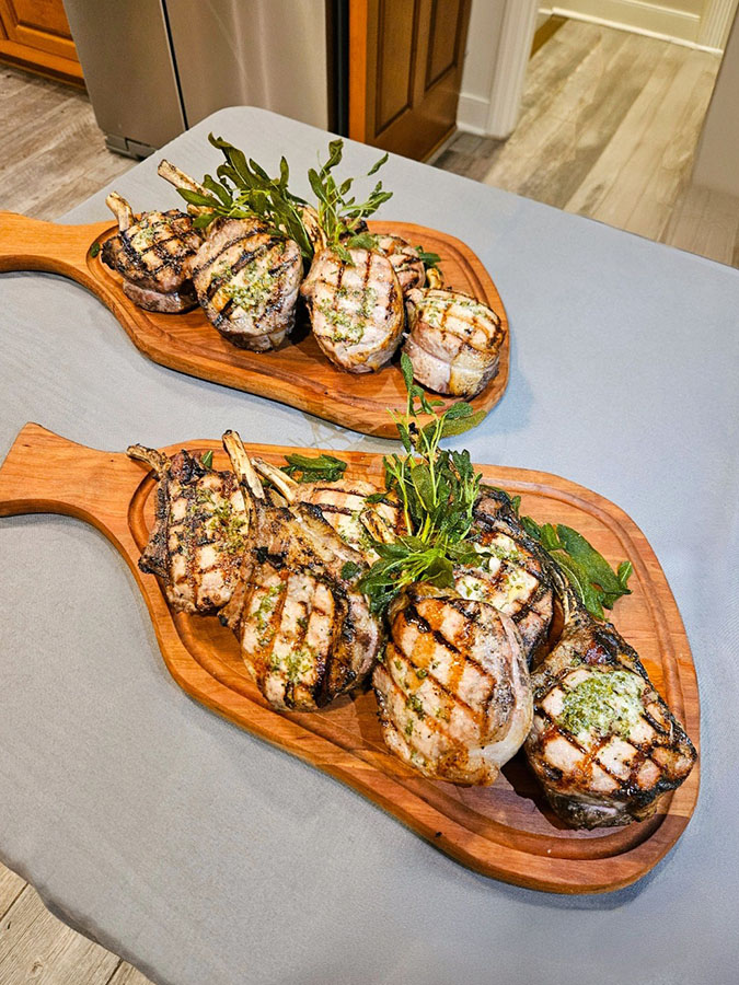 Two platters of grilled cooked meat on wooden serving boards.